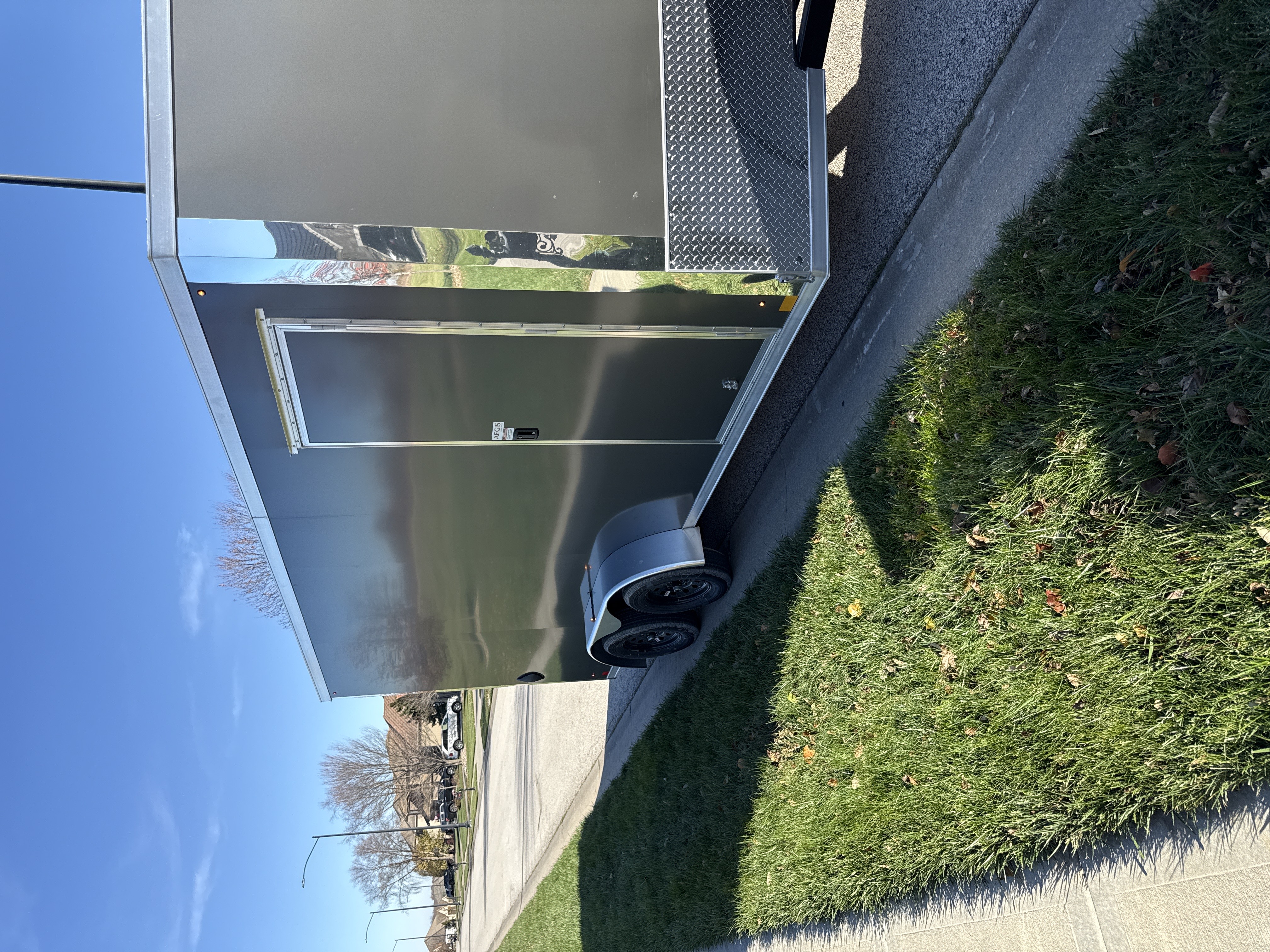 Enclosed cargo trailer exterior side angle view showing dual tandem axles and diamond plate fenders