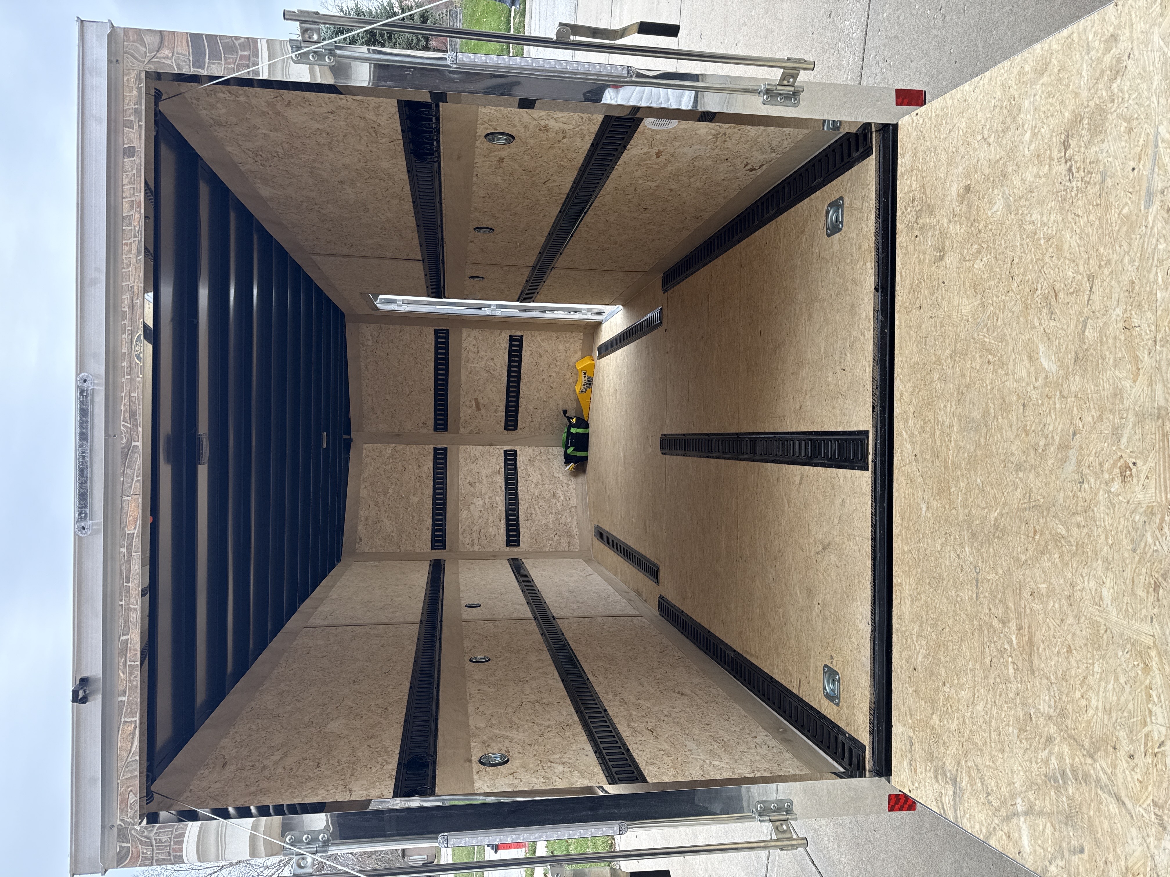Interior view of empty 16 foot enclosed trailer showing plywood lined walls with E-track tie-down system and LED lighting