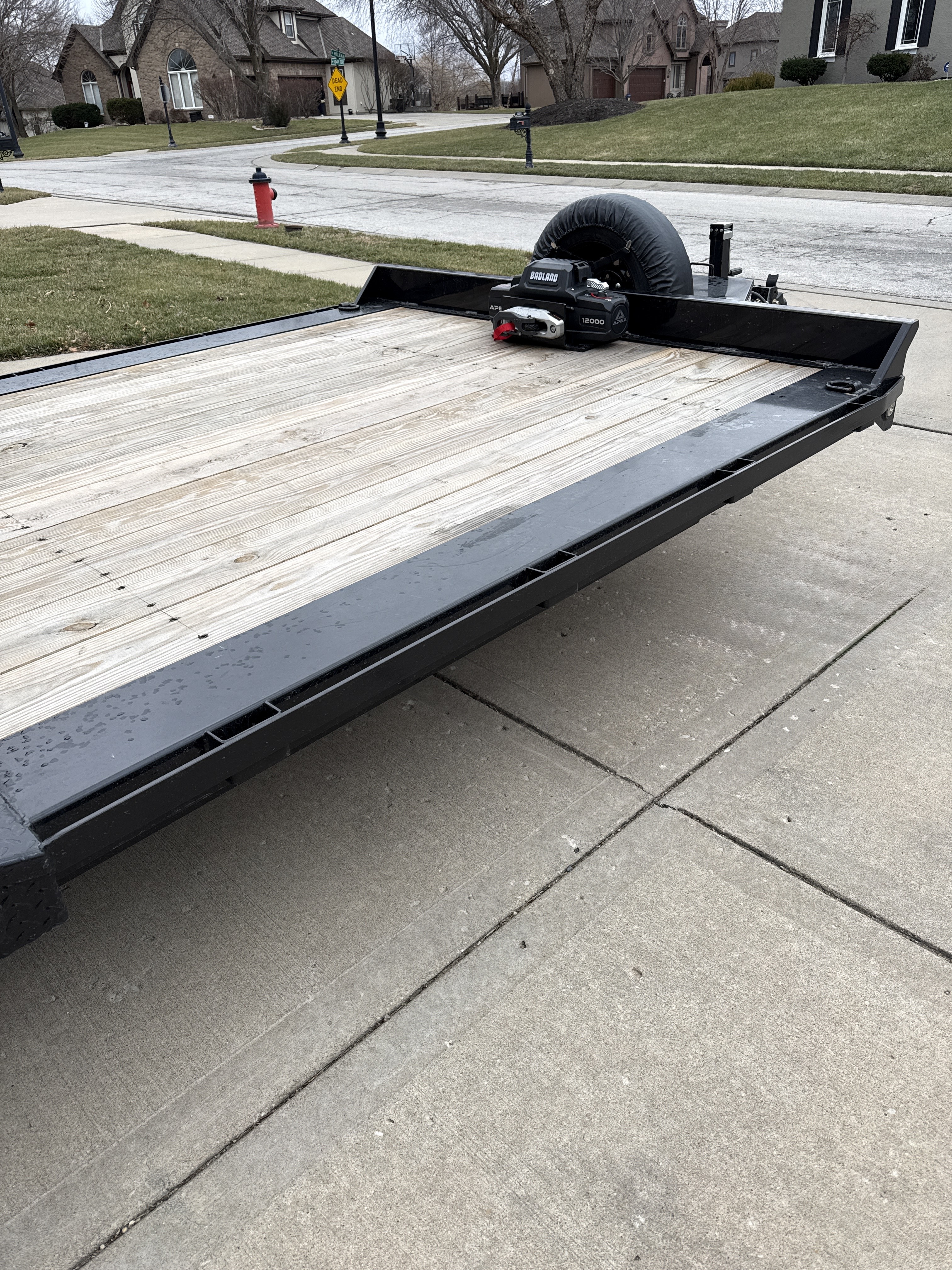 Side angle view of 22ft flatbed showing wooden deck surface and dual tandem axles